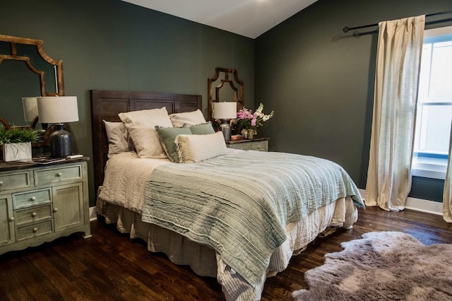 bedroom featuring baseboards, wood finished floors, and vaulted ceiling