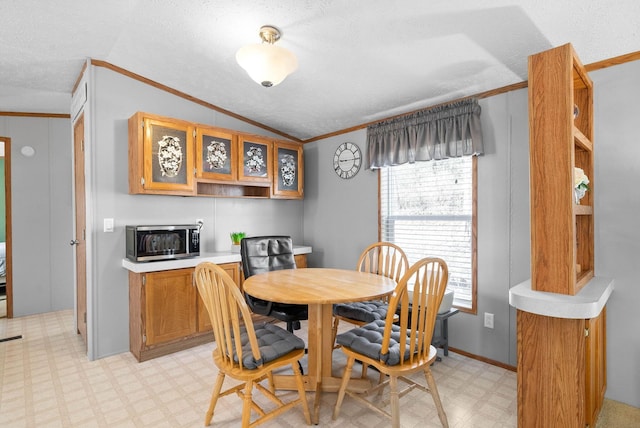 dining space featuring a textured ceiling, lofted ceiling, light floors, and ornamental molding