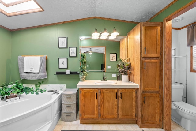 bathroom with toilet, vanity, a garden tub, vaulted ceiling with skylight, and a textured ceiling