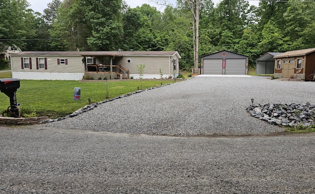 manufactured / mobile home with a detached garage, an outbuilding, and a front lawn