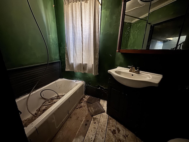 full bath with vanity, a bath, and wood finished floors