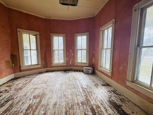 empty room with hardwood / wood-style floors, plenty of natural light, and ornamental molding