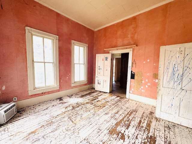 empty room with baseboards, an AC wall unit, wood finished floors, and crown molding