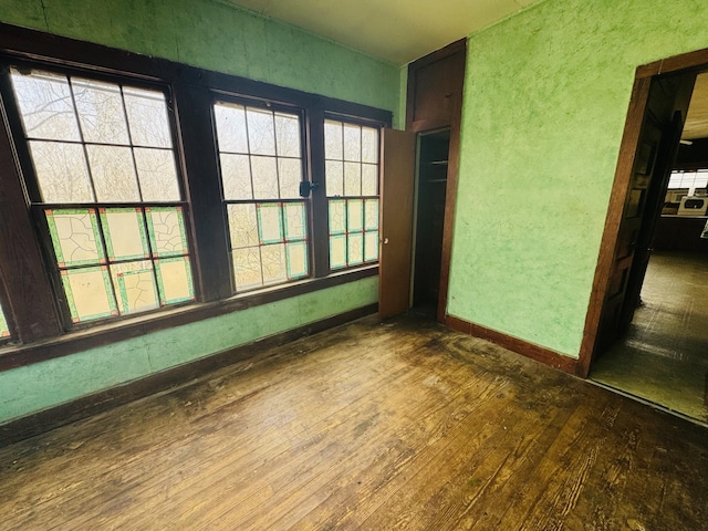 spare room featuring baseboards and wood-type flooring