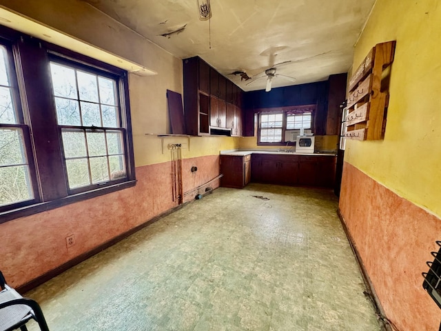 kitchen with white microwave, open shelves, ceiling fan, light floors, and a sink