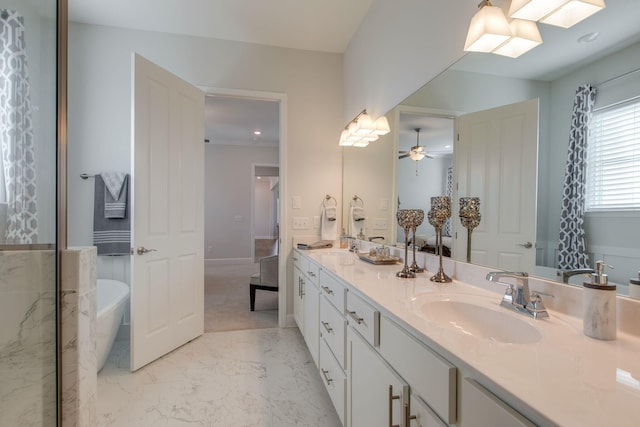 bathroom featuring marble finish floor, a sink, double vanity, a freestanding bath, and ceiling fan