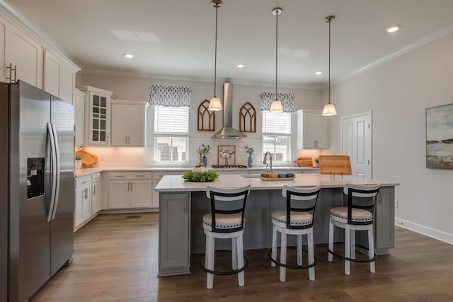 kitchen with dark wood finished floors, stainless steel appliances, light countertops, wall chimney exhaust hood, and tasteful backsplash