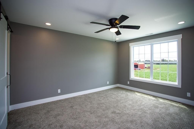 carpeted spare room with visible vents, baseboards, recessed lighting, ceiling fan, and a barn door