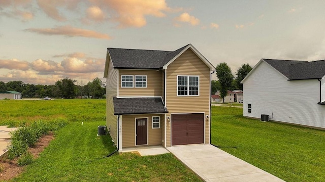 view of front facade featuring a lawn, a garage, driveway, and roof with shingles