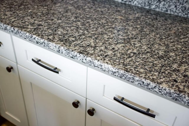 details with stone countertops and white cabinetry