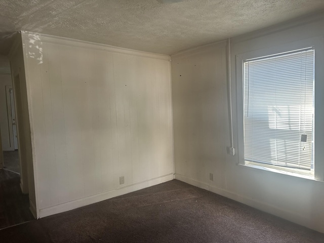 empty room with dark carpet and a textured ceiling