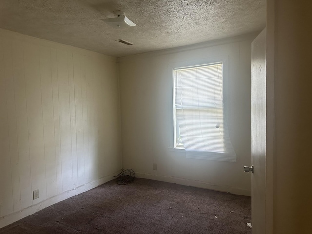 empty room with visible vents, a textured ceiling, and carpet