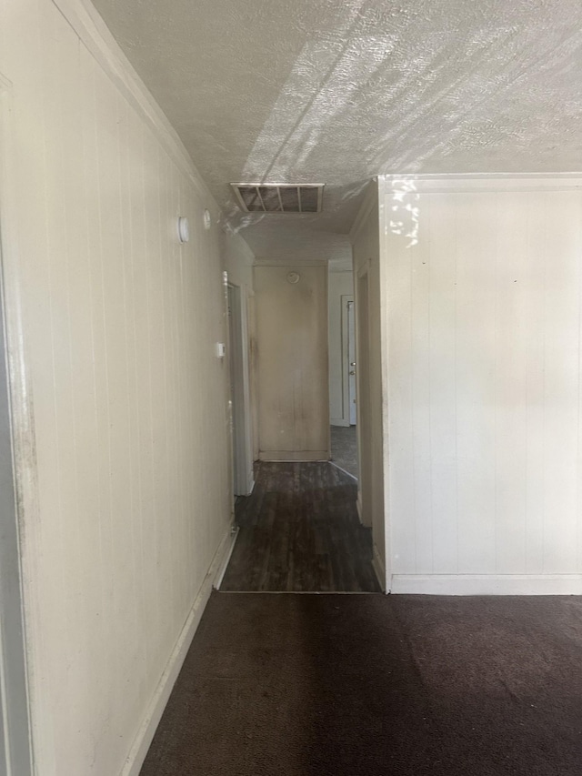 hall with ornamental molding, visible vents, carpet floors, and a textured ceiling