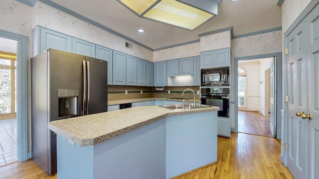 kitchen with light wood-type flooring, visible vents, black appliances, a sink, and wallpapered walls