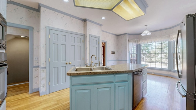 kitchen featuring wallpapered walls, ornamental molding, a sink, stainless steel appliances, and blue cabinets