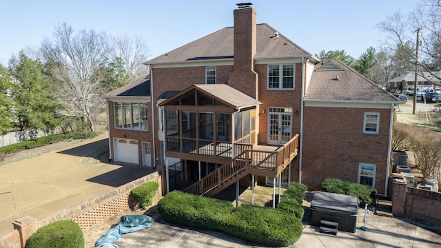 back of property featuring brick siding, a hot tub, stairway, a chimney, and a sunroom