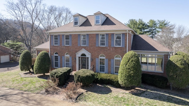 view of front of house with brick siding and roof with shingles