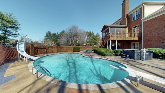 view of pool featuring stairway, a water slide, a wooden deck, a diving board, and a hot tub