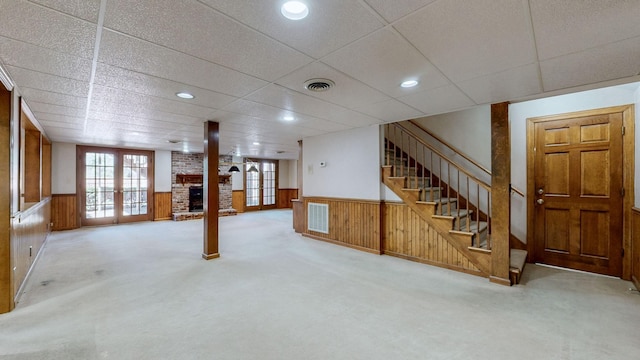 basement featuring a wainscoted wall, french doors, carpet, wood walls, and stairs