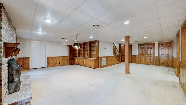 finished below grade area featuring visible vents, light colored carpet, and a wainscoted wall