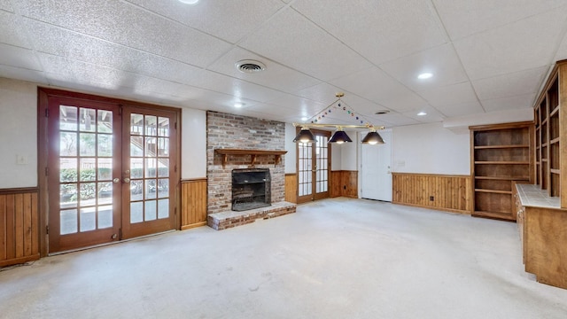 unfurnished living room featuring a wainscoted wall, visible vents, and french doors