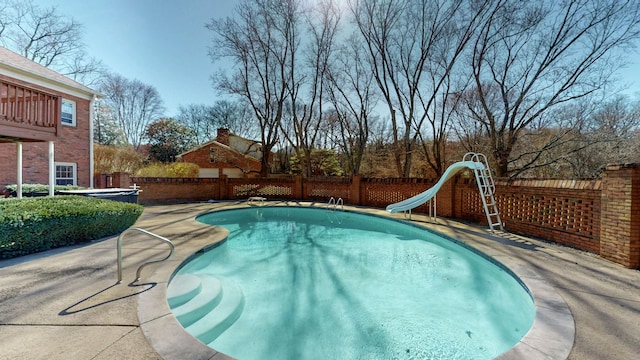 view of swimming pool with a fenced in pool, a water slide, a fenced backyard, and a patio area