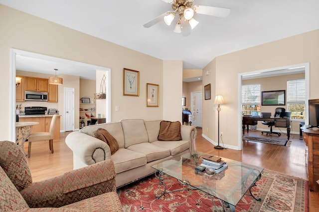 living room with baseboards, light wood-style flooring, and a ceiling fan