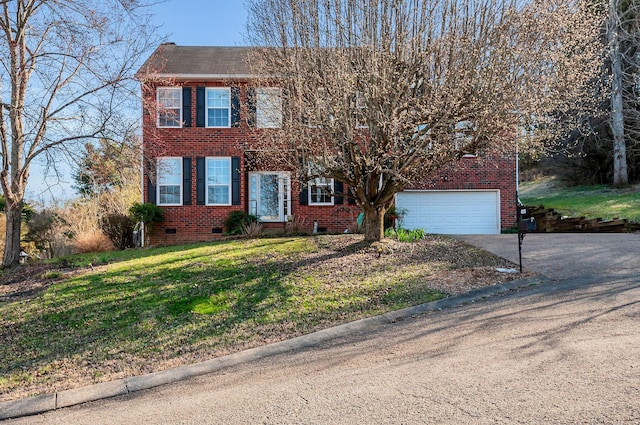 colonial-style house featuring a front yard, driveway, an attached garage, crawl space, and brick siding