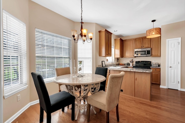 dining room with a chandelier, baseboards, and wood finished floors