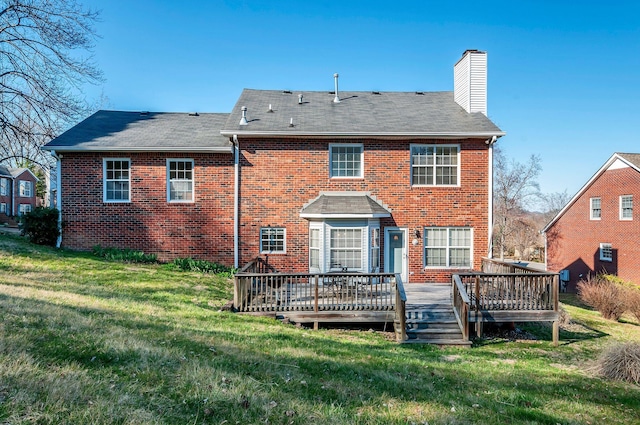 back of property featuring a deck, a lawn, brick siding, and a chimney