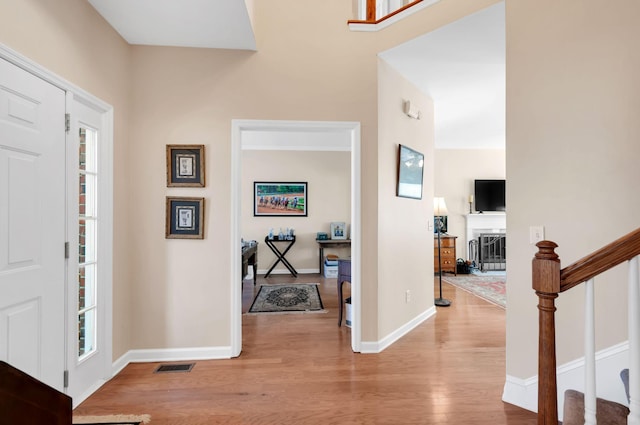 foyer entrance featuring visible vents, baseboards, stairway, a fireplace, and wood finished floors