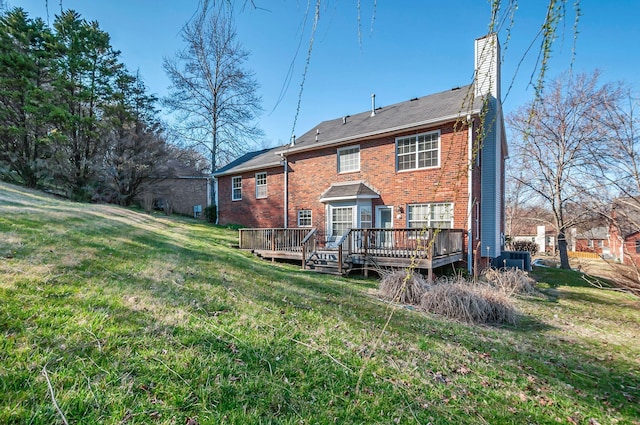 rear view of house with a lawn, a deck, central AC, brick siding, and a chimney