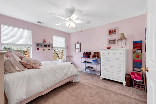 bedroom with visible vents, light colored carpet, and ceiling fan