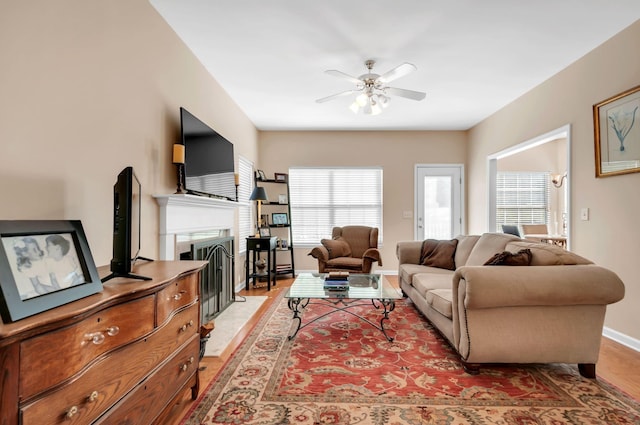 living area featuring a ceiling fan, a fireplace, and baseboards