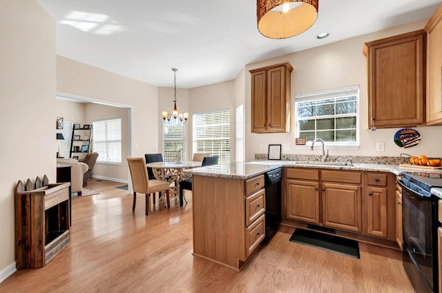 kitchen with a sink, light wood-type flooring, black appliances, and a peninsula