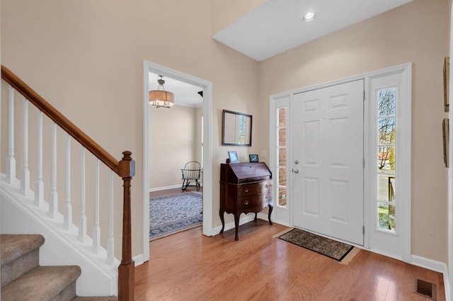 entrance foyer with stairs, light wood-style floors, visible vents, and baseboards