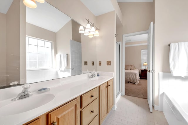 ensuite bathroom with tile patterned flooring, double vanity, a bathtub, and a sink