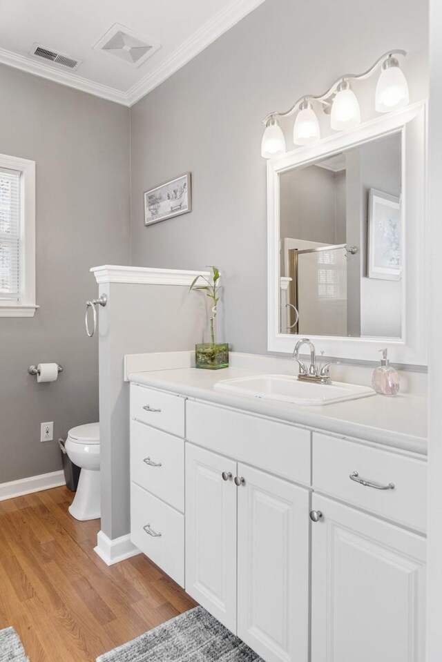 bathroom featuring a shower stall, visible vents, wood finished floors, and ornamental molding