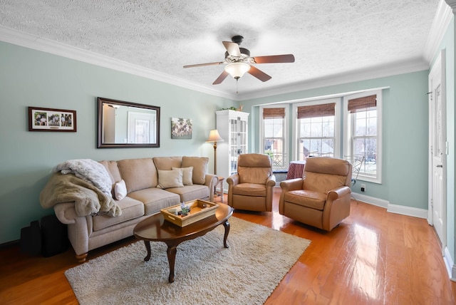 living area featuring ceiling fan, light wood-type flooring, baseboards, and ornamental molding