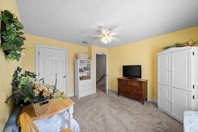 sitting room featuring visible vents, baseboards, ceiling fan, light colored carpet, and a textured ceiling