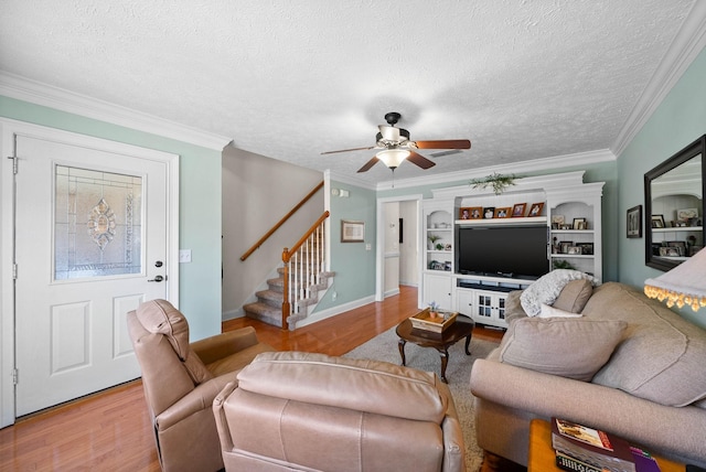 living room featuring stairs, crown molding, light wood-style floors, and a textured ceiling