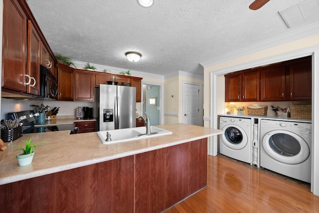 kitchen featuring washing machine and clothes dryer, a peninsula, electric range oven, stainless steel refrigerator with ice dispenser, and black microwave