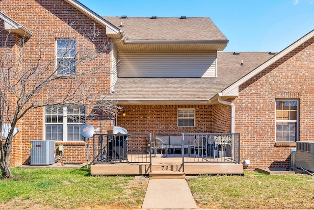 rear view of property with a wooden deck, central AC unit, brick siding, and a shingled roof