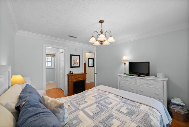 bedroom featuring visible vents, a textured ceiling, an inviting chandelier, and ornamental molding