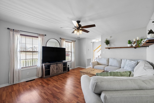 living area with visible vents, wood finished floors, baseboards, ceiling fan, and stairs