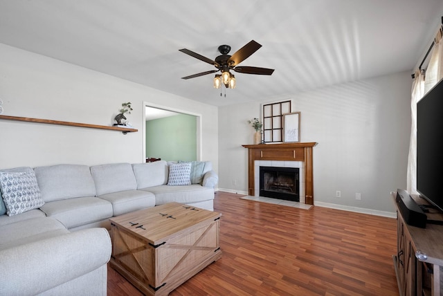 living area with ceiling fan, baseboards, wood finished floors, and a tile fireplace