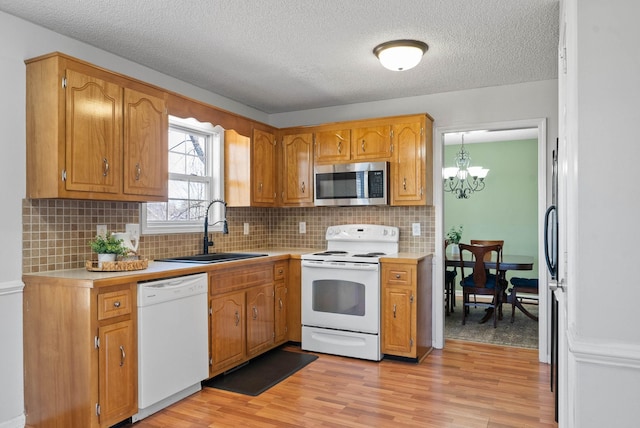 kitchen featuring light countertops, light wood-type flooring, decorative backsplash, appliances with stainless steel finishes, and a sink