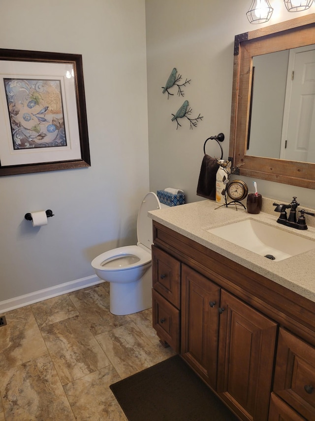 half bath with vanity, toilet, and baseboards