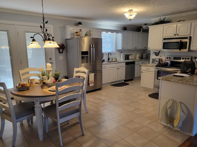 kitchen featuring pendant lighting, ornamental molding, a sink, white cabinetry, and stainless steel appliances