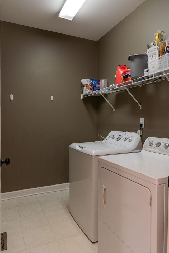 washroom featuring light tile patterned floors, laundry area, washer and dryer, and baseboards